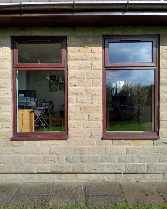 Before: two brown-framed windows in the stone wall