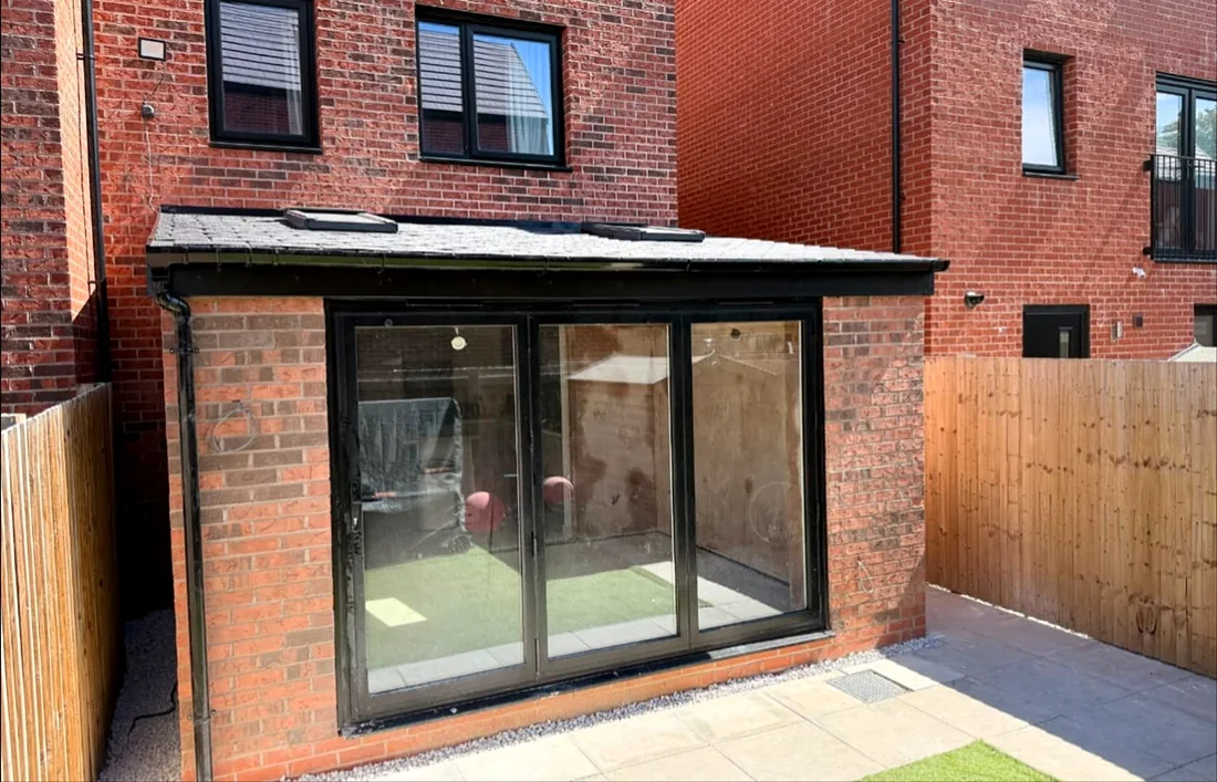 Brick rear extension with black-framed bifold doors and a slate-grey roof