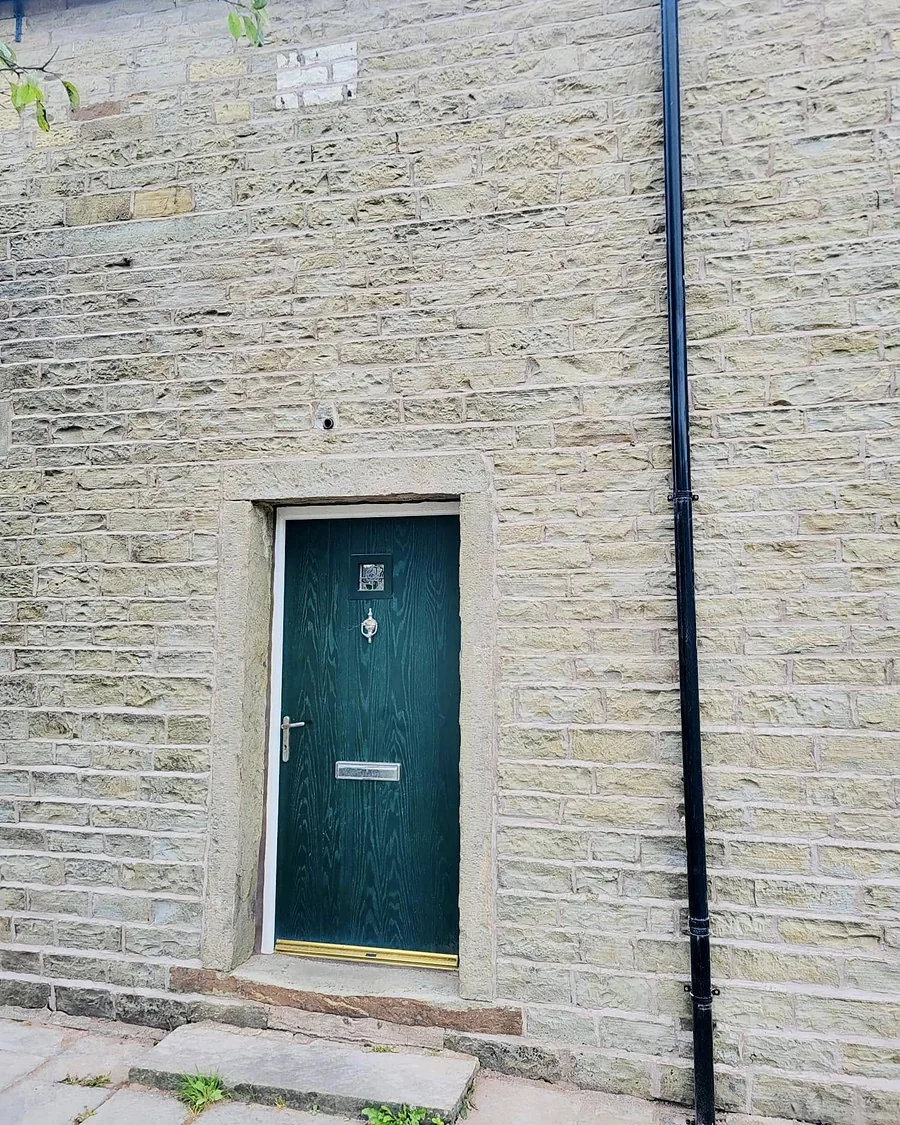 Repointed stone front of a house in Whitworth with a green door