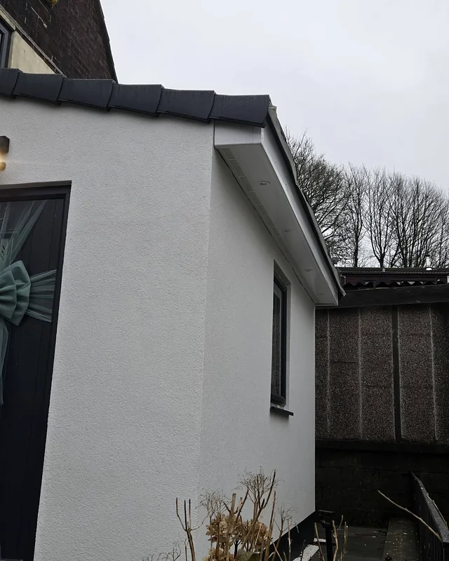 The same side extension finished in white render with a dark roof edge