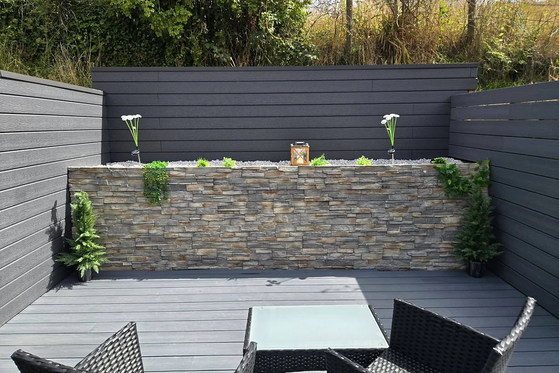 Grey composite deck and cladding round a stone-faced planter wall