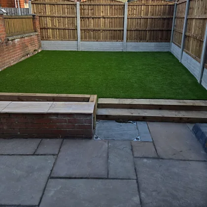 Artificial grass edged with timber sleepers above a new patio