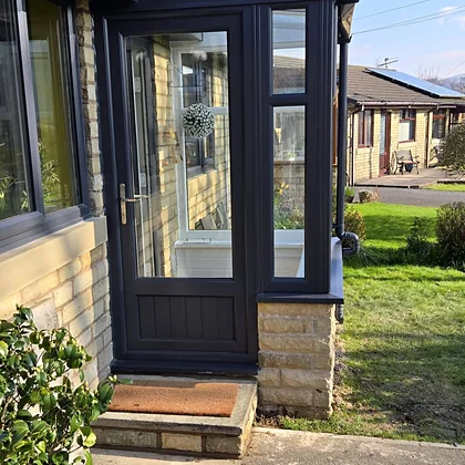 Stone porch with an anthracite door and side glazing